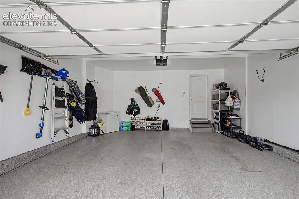 Image 31 of 35: Spacious garage featuring a durable epoxy floor, white painted walls, and a