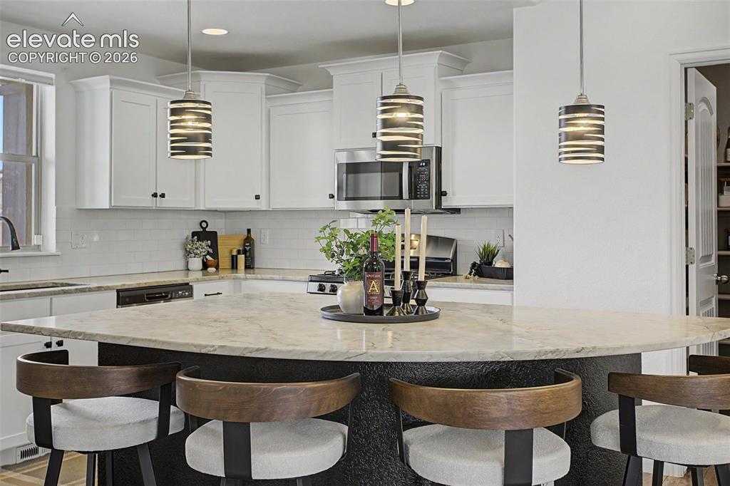 Image 6 of 35: Kitchen featuring a large island with Quartzite "weathered" countertop, whi