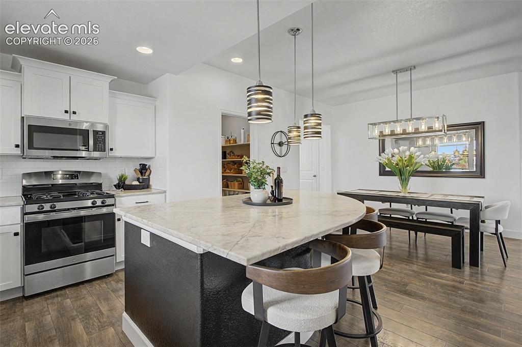 Image 7 of 35: Kitchen and dining area featuring a curved island 