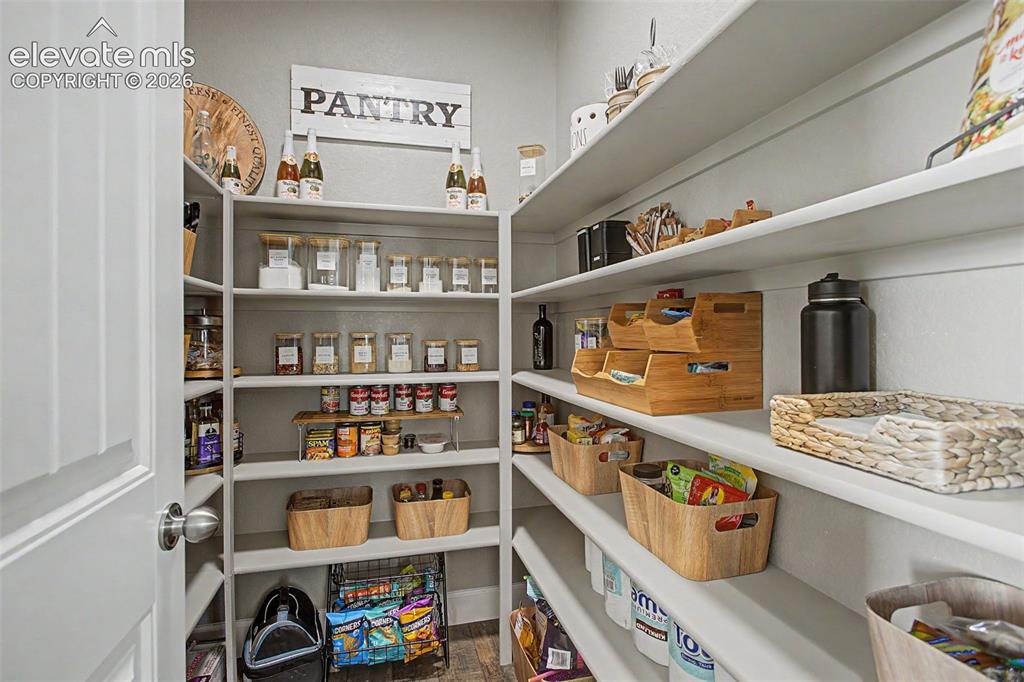 Image 9 of 35: Walk-in pantry featuring wood built-in shelving, white paneled door, LVP fi