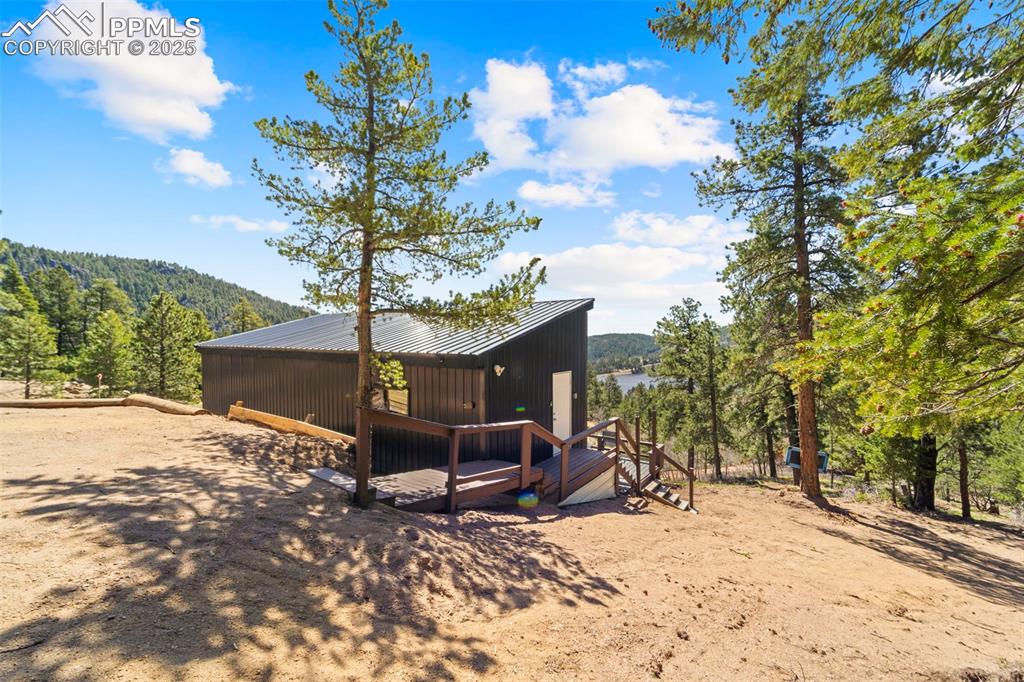 Image 17 of 35: Back of property featuring a forest view and metal roof