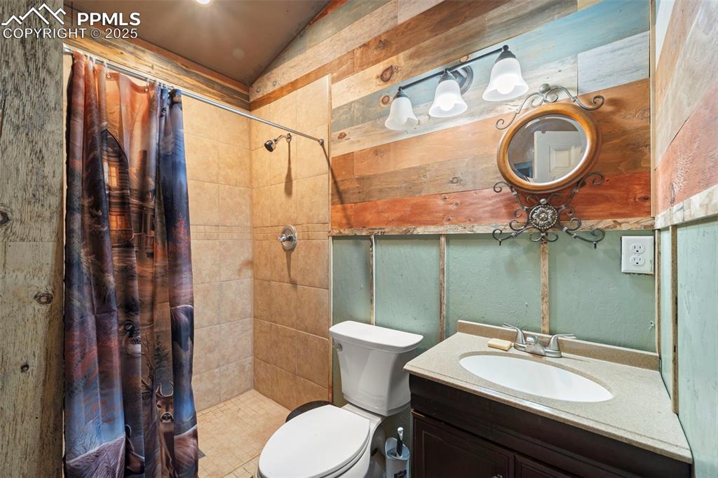 Image 18 of 35: Full bath with lofted ceiling, a tile shower, toilet, and vanity