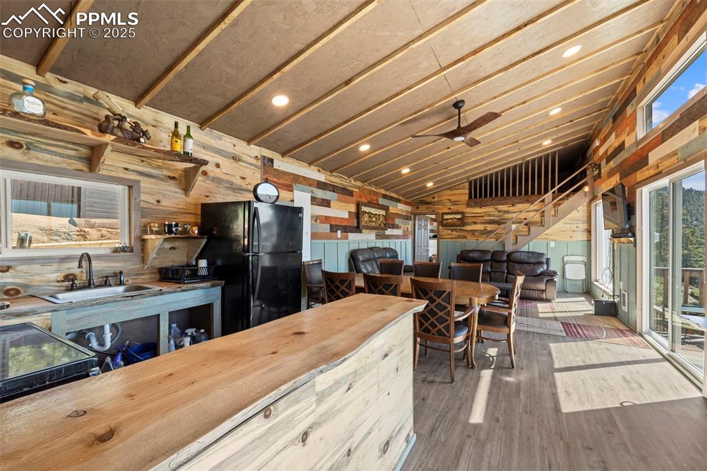 Image 19 of 35: Kitchen with freestanding refrigerator, a sink, wooden walls, vaulted ceili