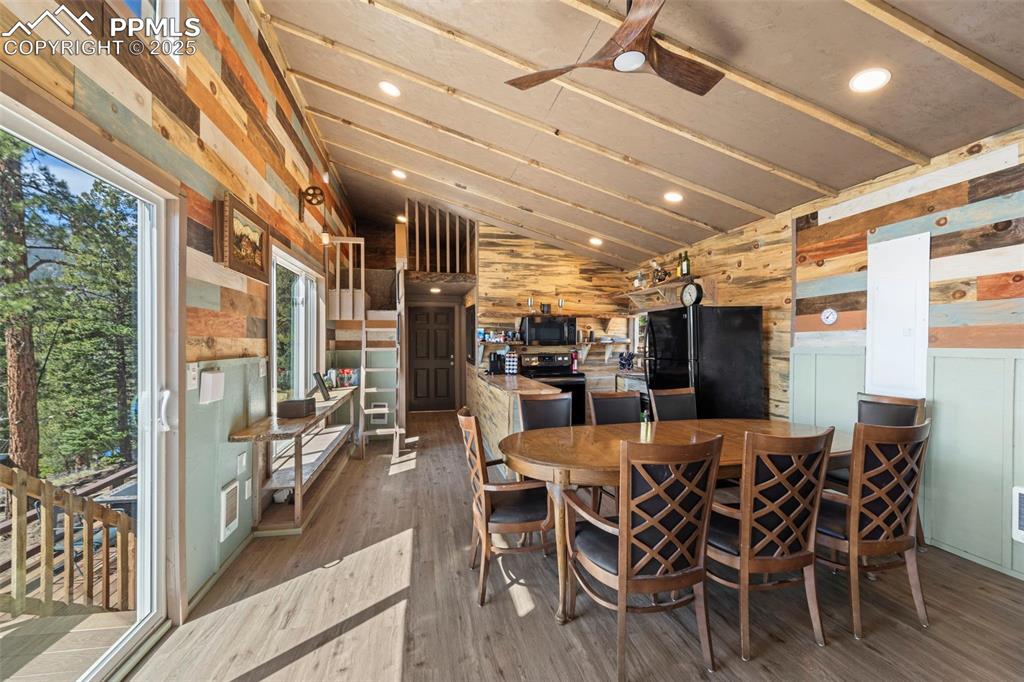 Image 22 of 35: Dining room featuring wood walls, lofted ceiling, wood finished floors, cei