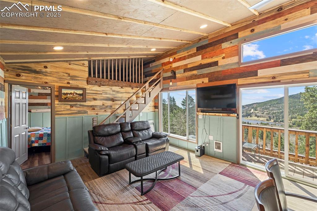 Image 24 of 35: Living area featuring wood walls, healthy amount of natural light, stairs, 
