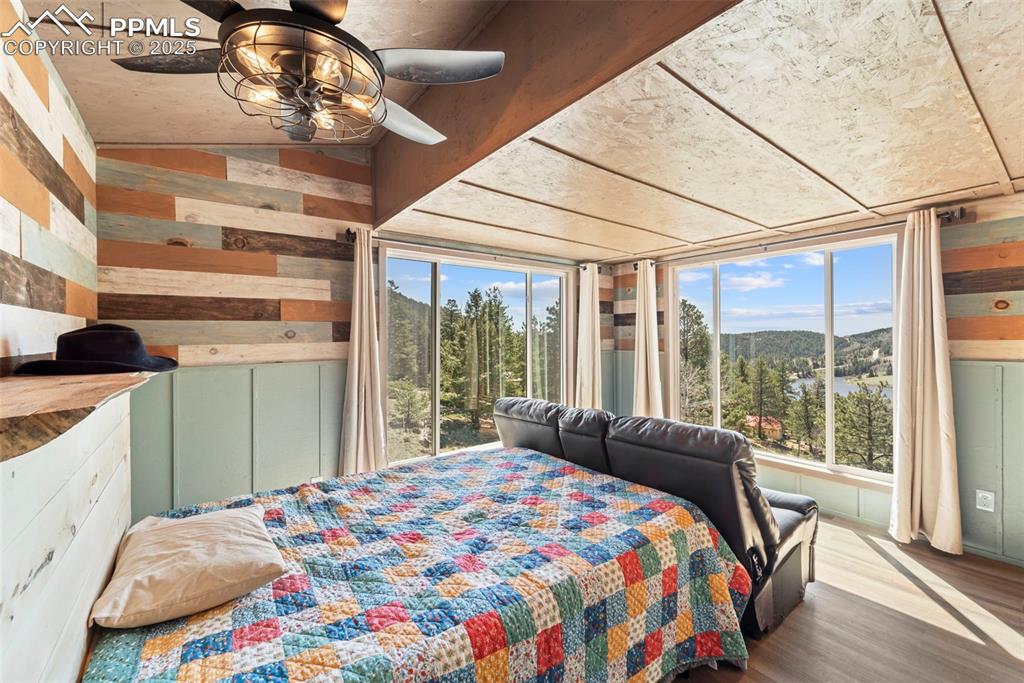 Image 25 of 35: Bedroom featuring wooden walls, a mountain view, wood finished floors, ceil
