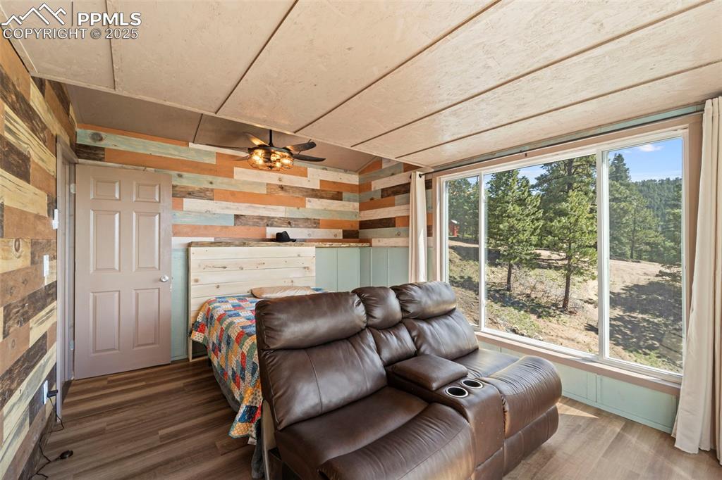 Image 26 of 35: Bedroom featuring multiple windows, wood walls, and wood finished floors
