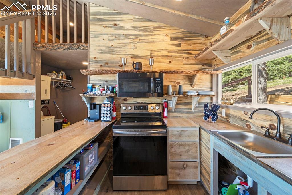 Image 31 of 35: Kitchen with stainless steel range with electric stovetop, wood counters, a
