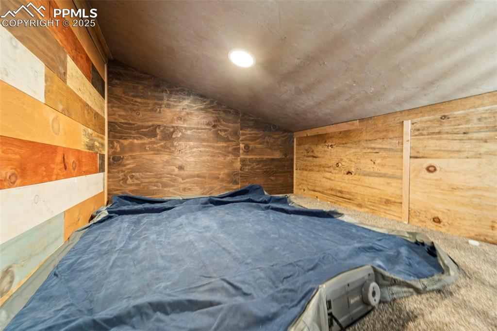 Image 33 of 35: Loft bedroom /vaulted ceiling, wooden walls, and carpet