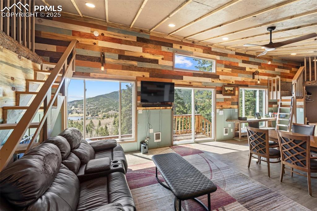 Image 5 of 35: Living room with a ceiling fan, stairway, wood walls, recessed lighting, an