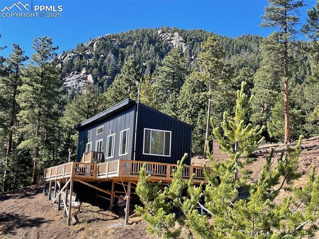 Image 6 of 35: View of property exterior featuring a wooden deck and a forest view