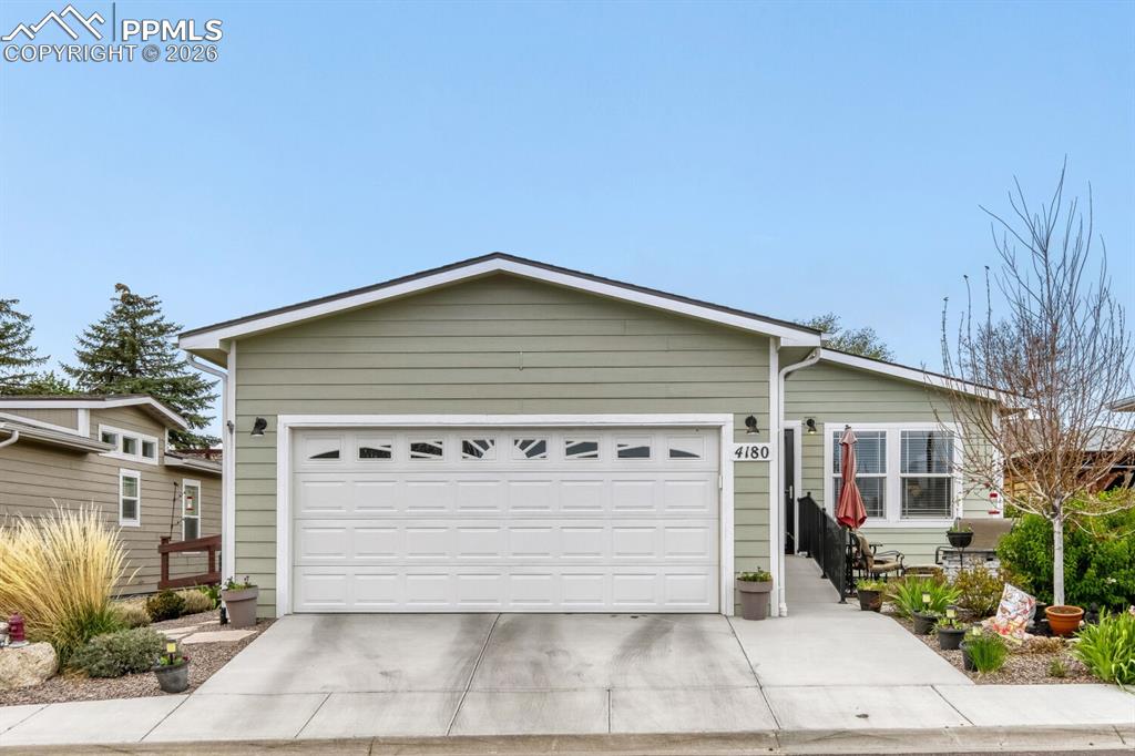 Image 1 of 33: Green siding exterior with a white garage door featuring transom windows