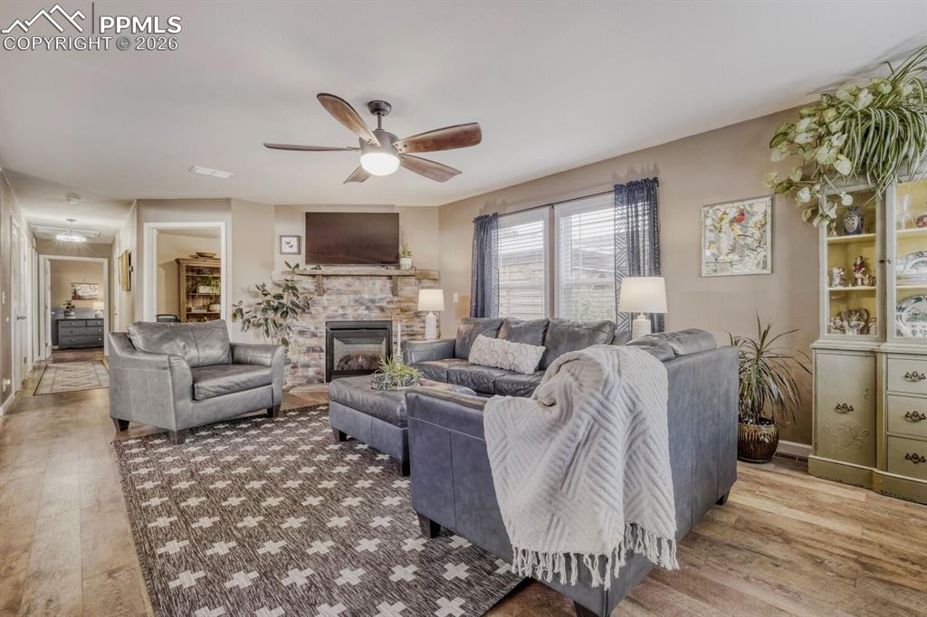 Image 6 of 33: Spacious living room featuring wood-finish flooring, a stone-clad fireplace