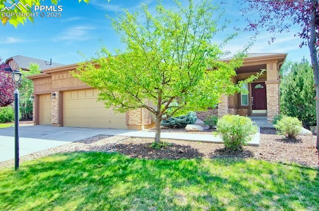 Caption: View of front of house featuring stone siding, driveway, a garage, and a front lawn