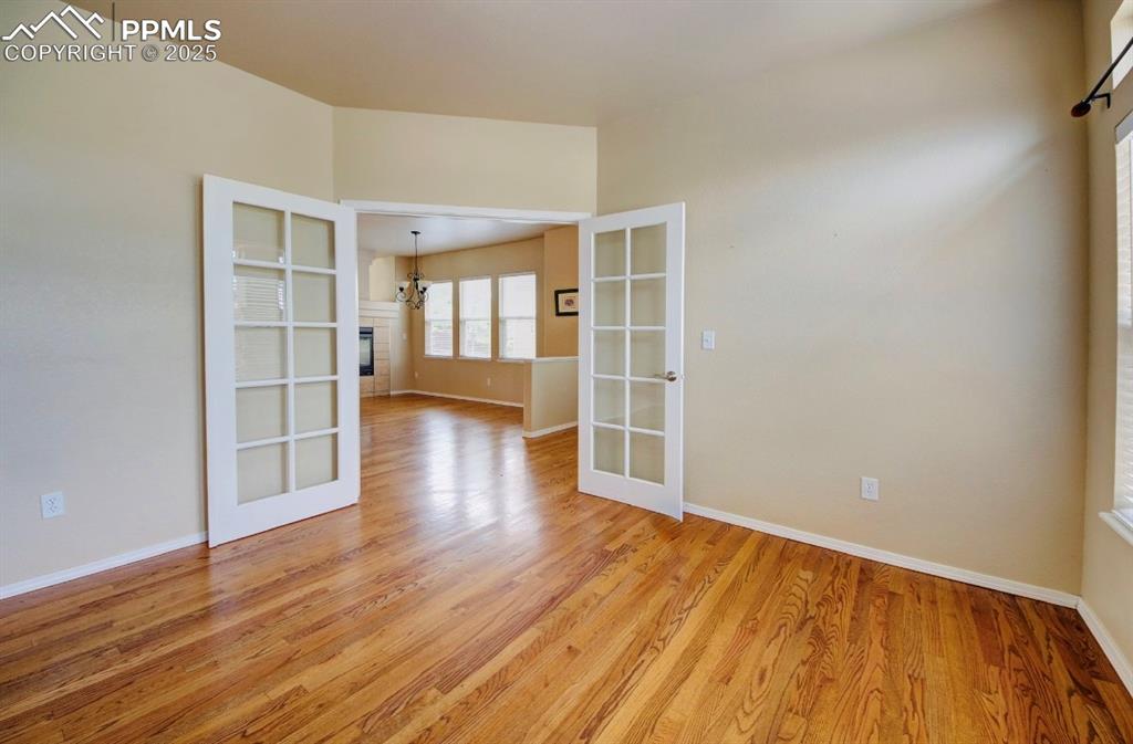 Image 10 of 42: Unfurnished room with light wood-style flooring, french doors, a tiled fire