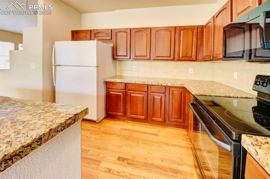 Image 13 of 42: Kitchen with stainless steel stove, black microwave, freestanding refrigera