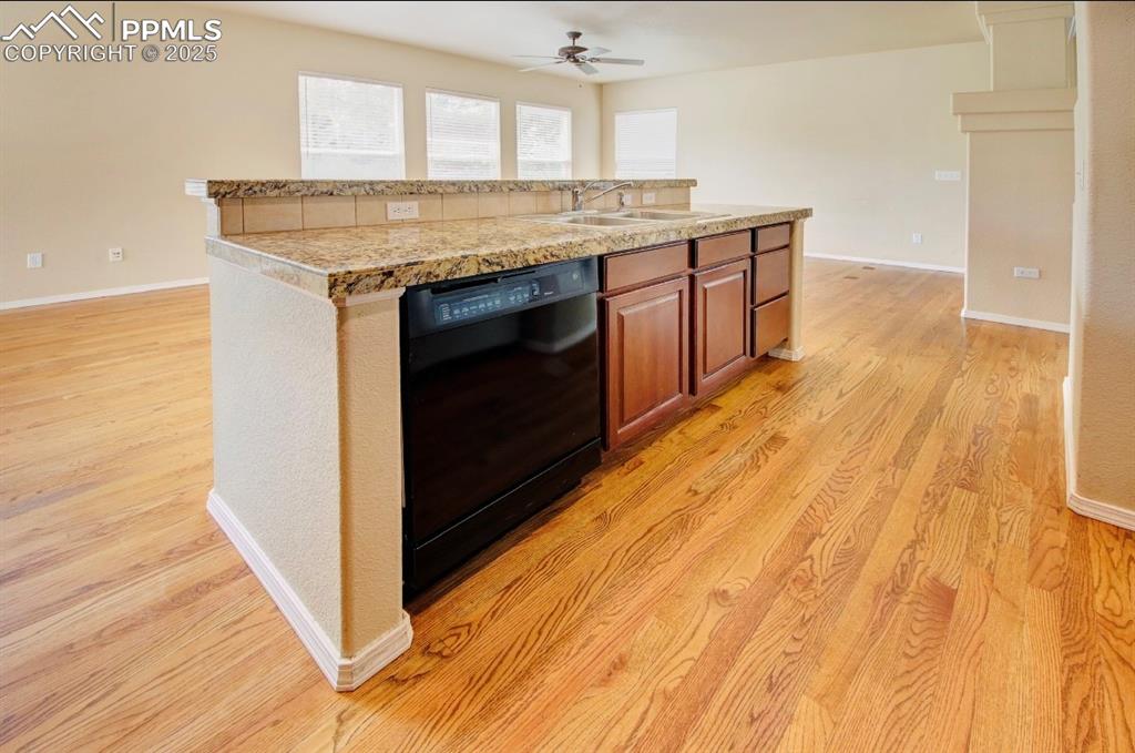 Image 15 of 42: Kitchen with light wood-type flooring, a kitchen island with sink, light co