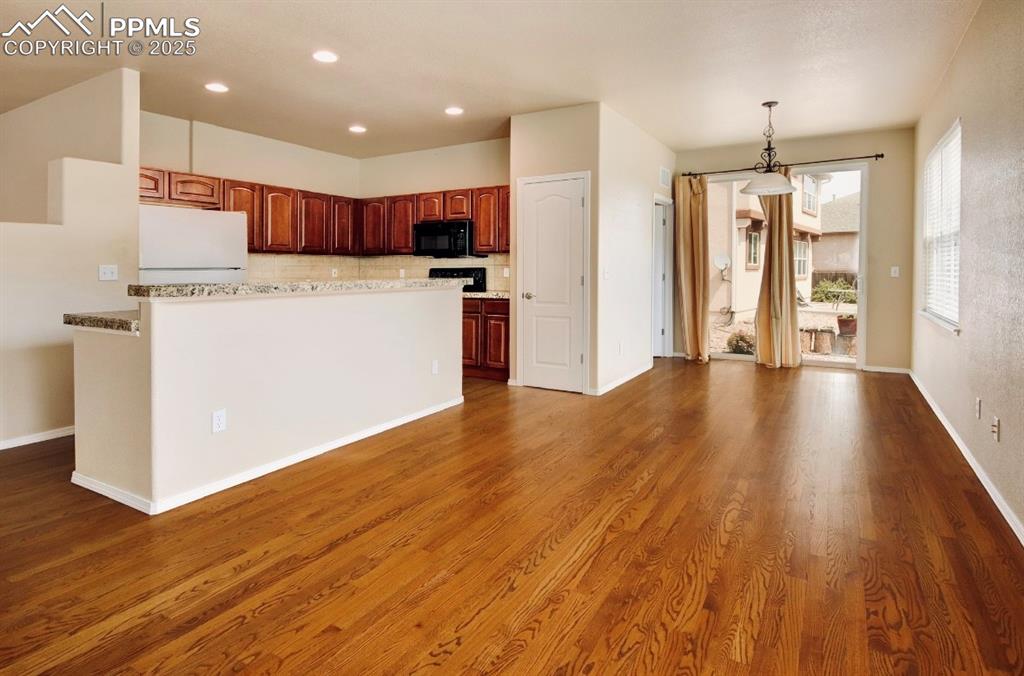 Image 18 of 42: Kitchen featuring freestanding refrigerator, backsplash, hanging light fixt