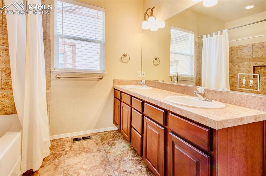 Image 23 of 42: Bathroom featuring shower / bath combination with curtain and light tile pa