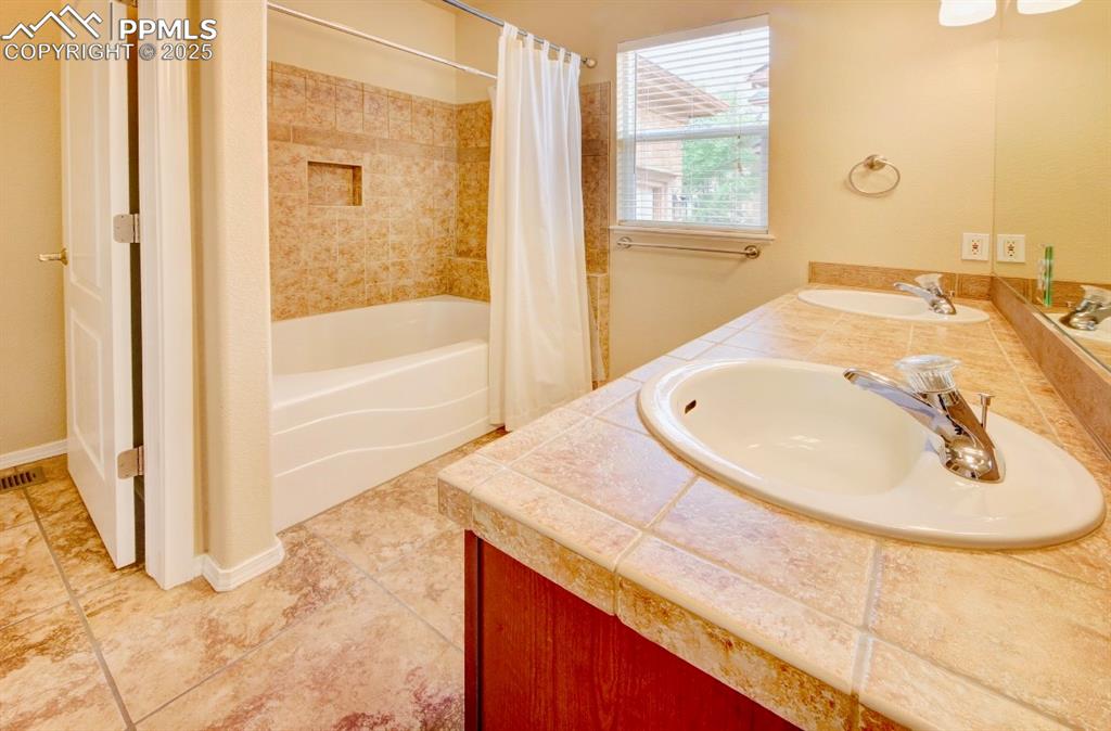 Image 24 of 42: Bathroom with shower / bath combination with curtain and light tile pattern