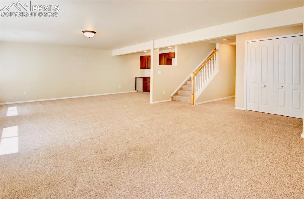 Image 27 of 42: Finished basement featuring light colored carpet and stairway