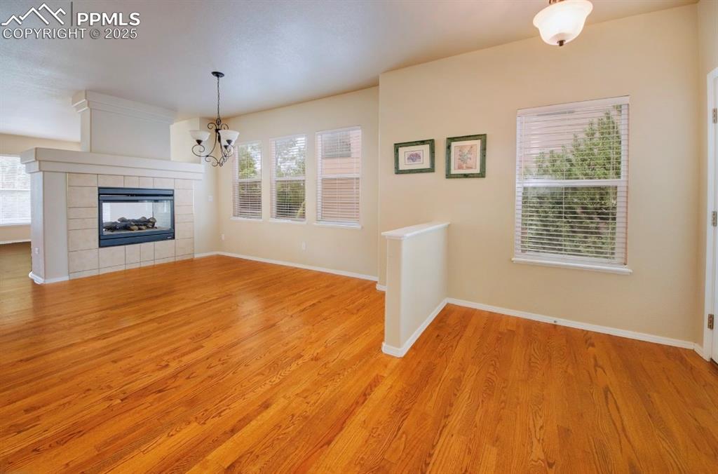 Image 7 of 42: Unfurnished living room with light wood finished floors and a tiled firepla
