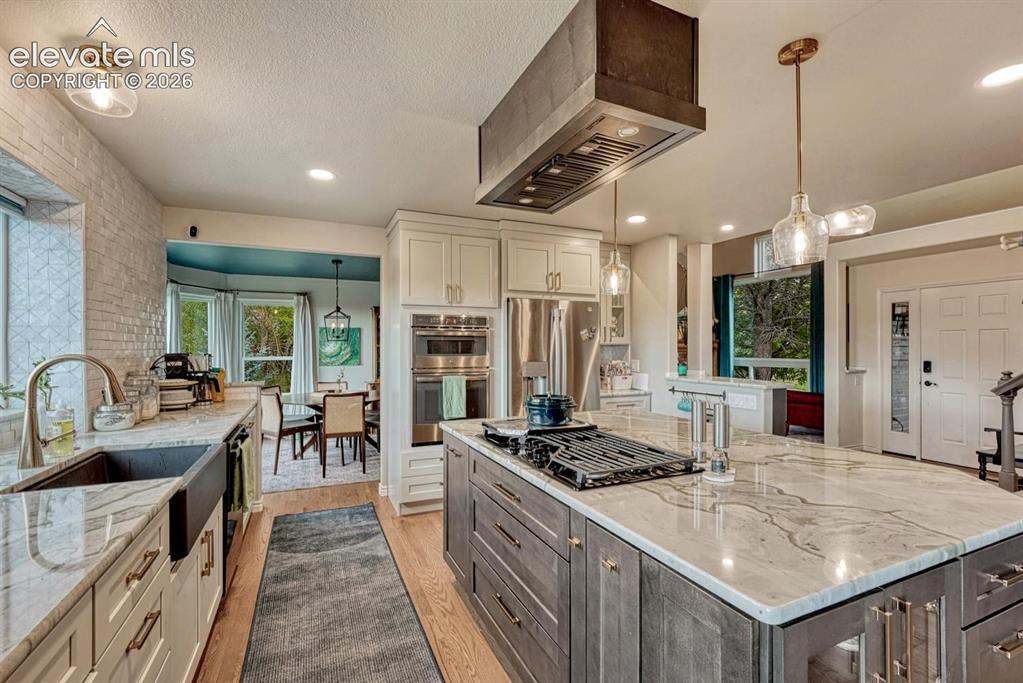 Image 11 of 41: Gourmet kitchen featuring a large central island with integrated cooktop, s