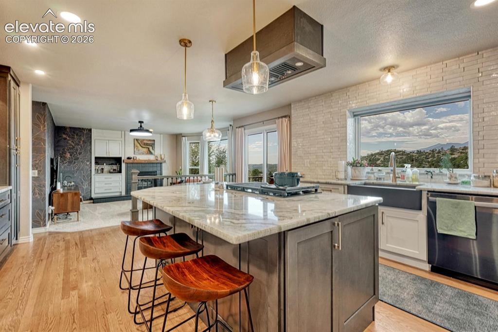 Image 13 of 41: Kitchen island with stone countertop, stainless steel appliances, wood floo