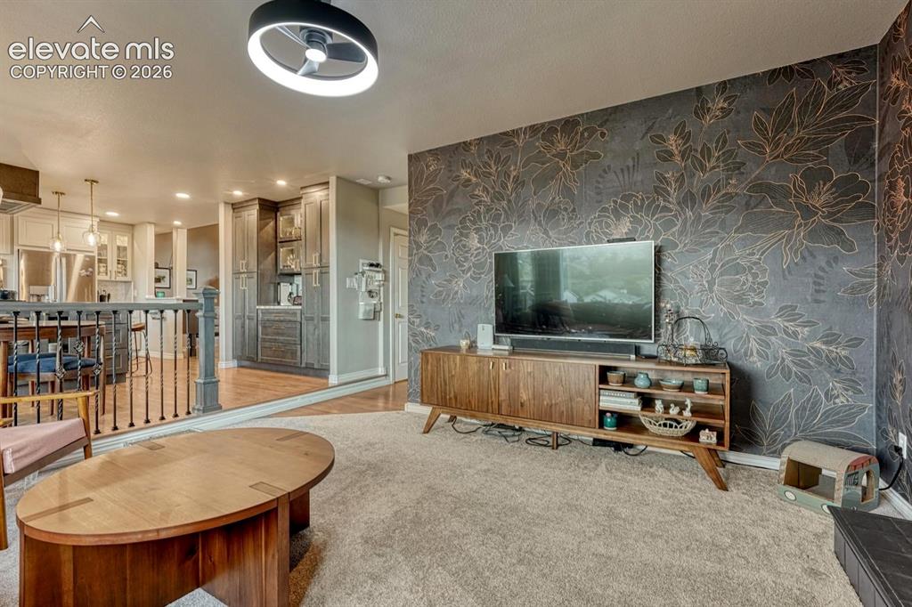 Image 18 of 41: Living space featuring a striking accent wall with botanical motif, plush c