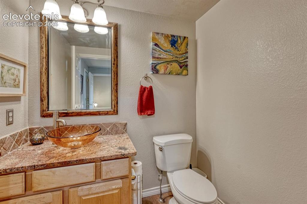 Image 19 of 41: Bathroom featuring a vessel sink, wood-finish vanity, granite countertop, a