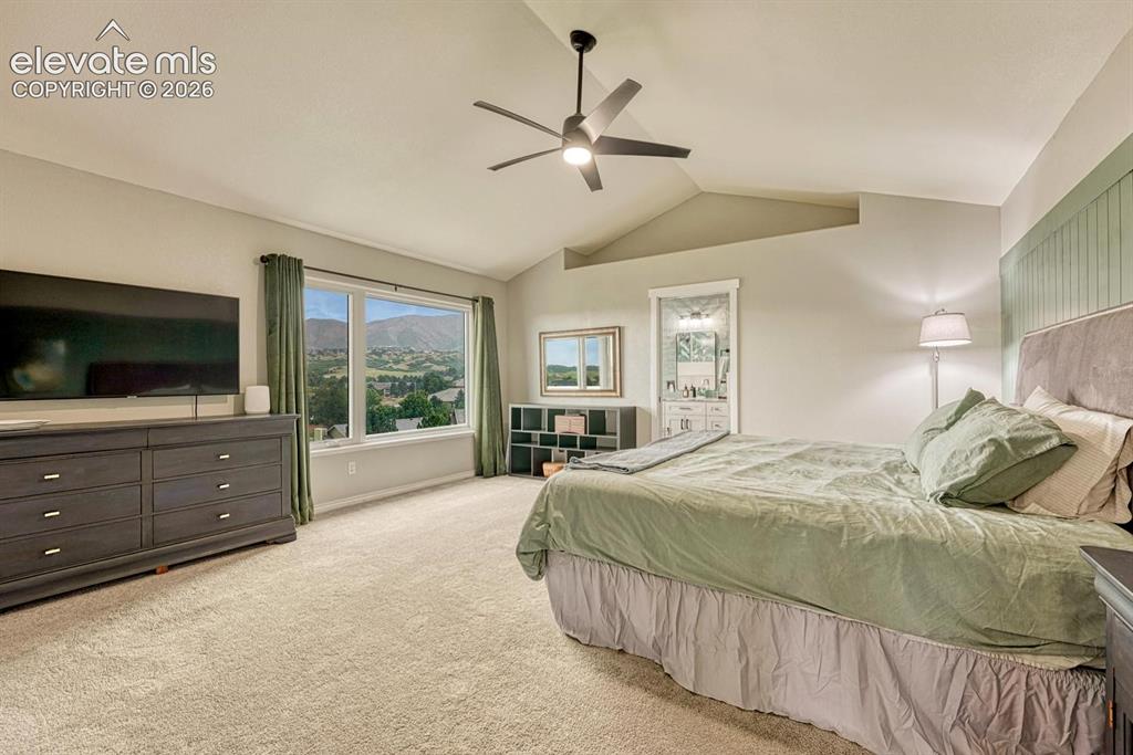 Image 20 of 41: Vaulted ceilings, a wide window, carpeted flooring, and an en-suite bathroo