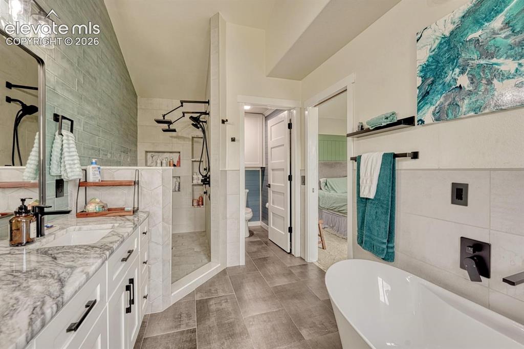 Image 22 of 41: Freestanding soaking tub, dual-head shower system, white shaker vanity, til