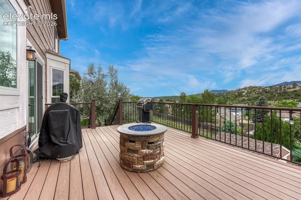 Image 31 of 41: Expansive deck featuring composite decking, metal railing, a stone fire pit