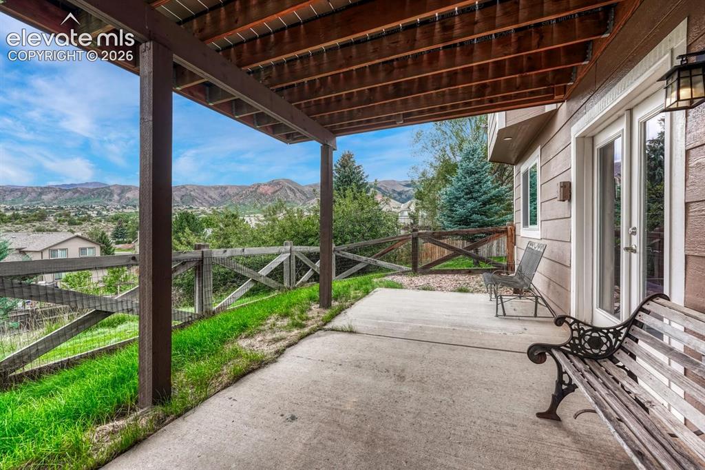 Image 32 of 41: Covered patio with concrete flooring, wood deck ceiling, and mountain scene