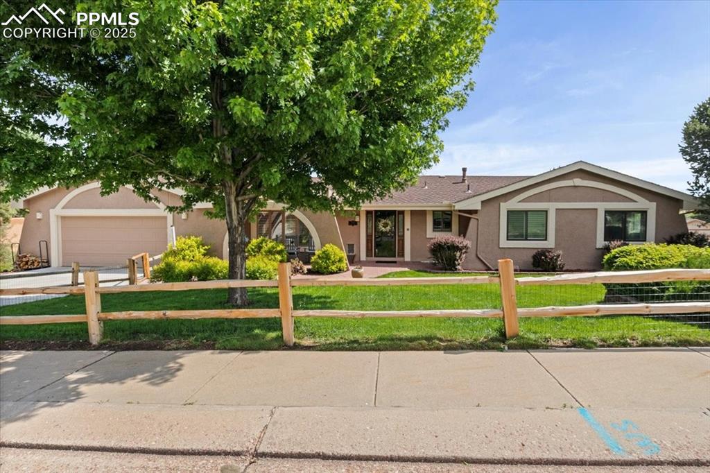 Caption: Ranch-style house with stucco siding, driveway, and an attached garage