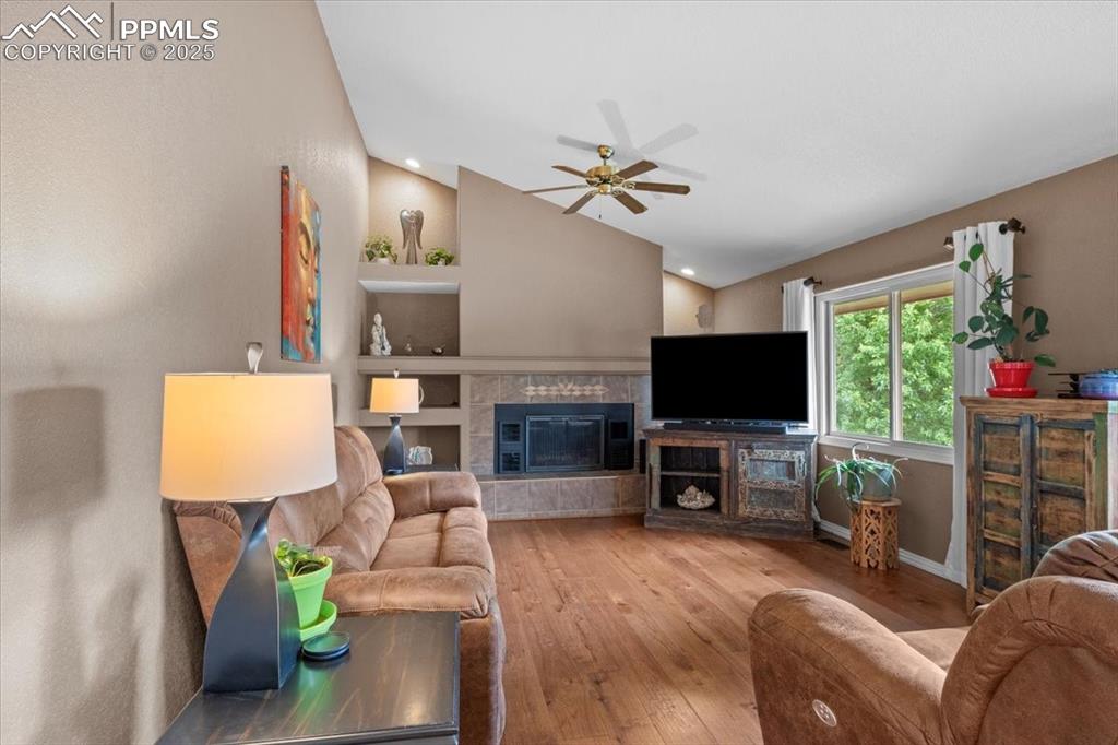 Image 13 of 49: Living area with vaulted ceiling, ceiling fan, wood-type flooring, built in