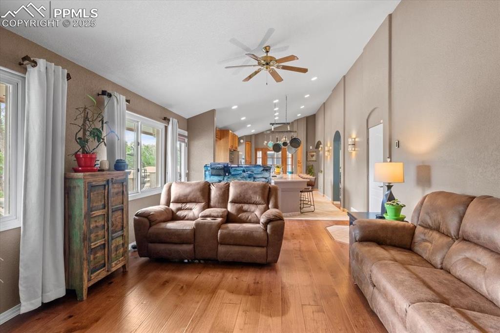 Image 14 of 49: Living area with a ceiling fan, lofted ceiling, light wood finished floors,