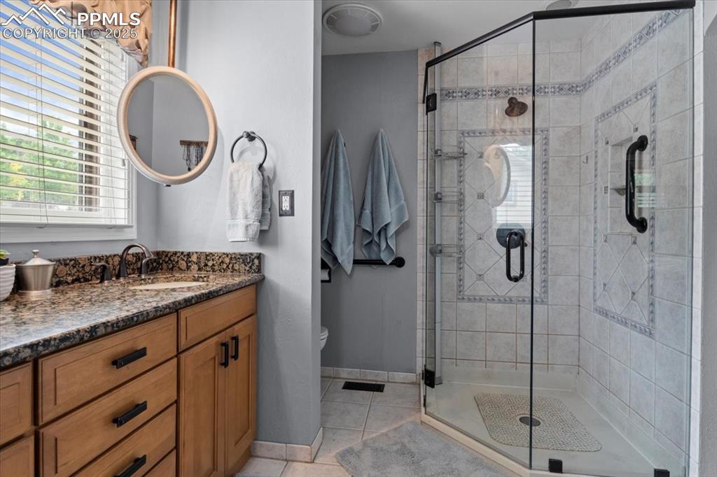 Image 23 of 49: Bathroom featuring tile patterned flooring, vanity, toilet, a shower stall,