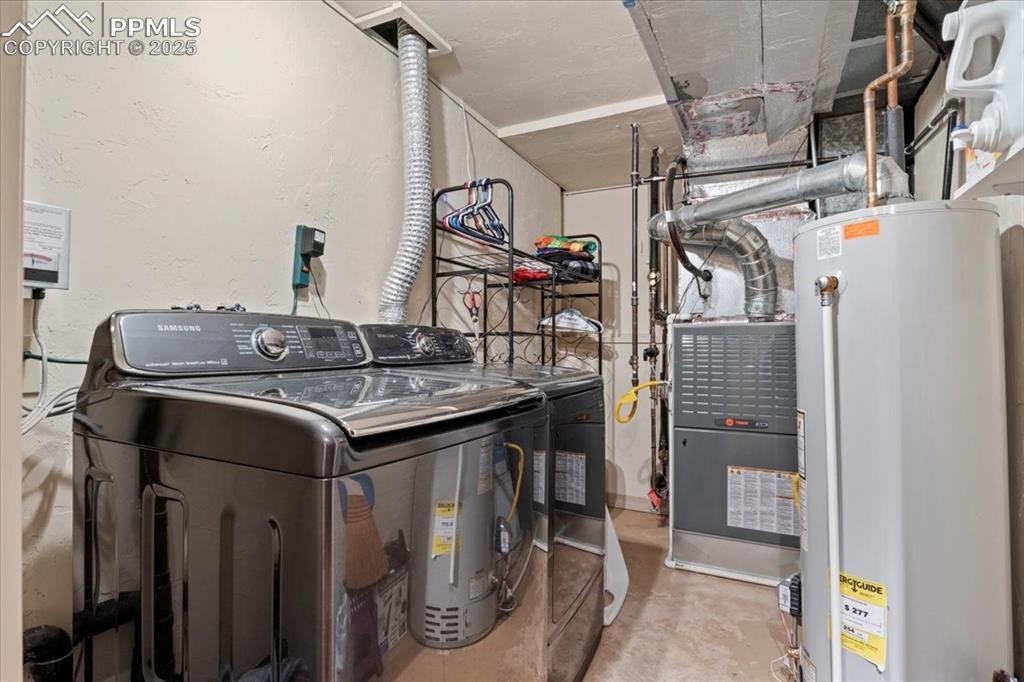 Image 30 of 49: Utility room with water heater and washer and clothes dryer