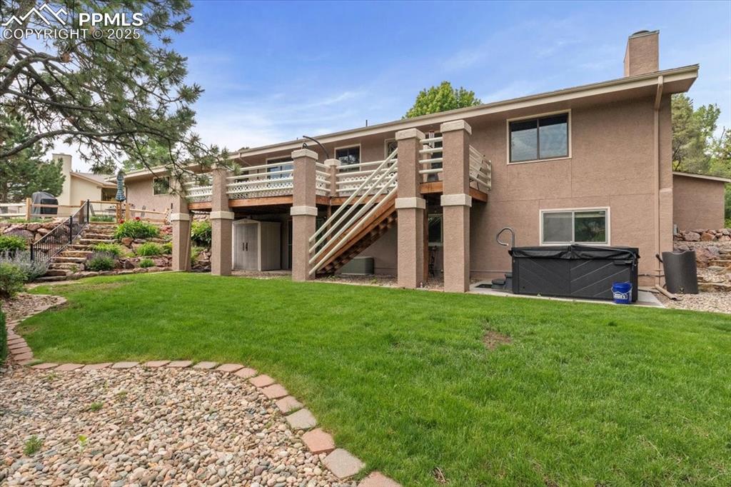 Image 39 of 49: Rear view of house with stairs, a hot tub, a deck, and stucco siding