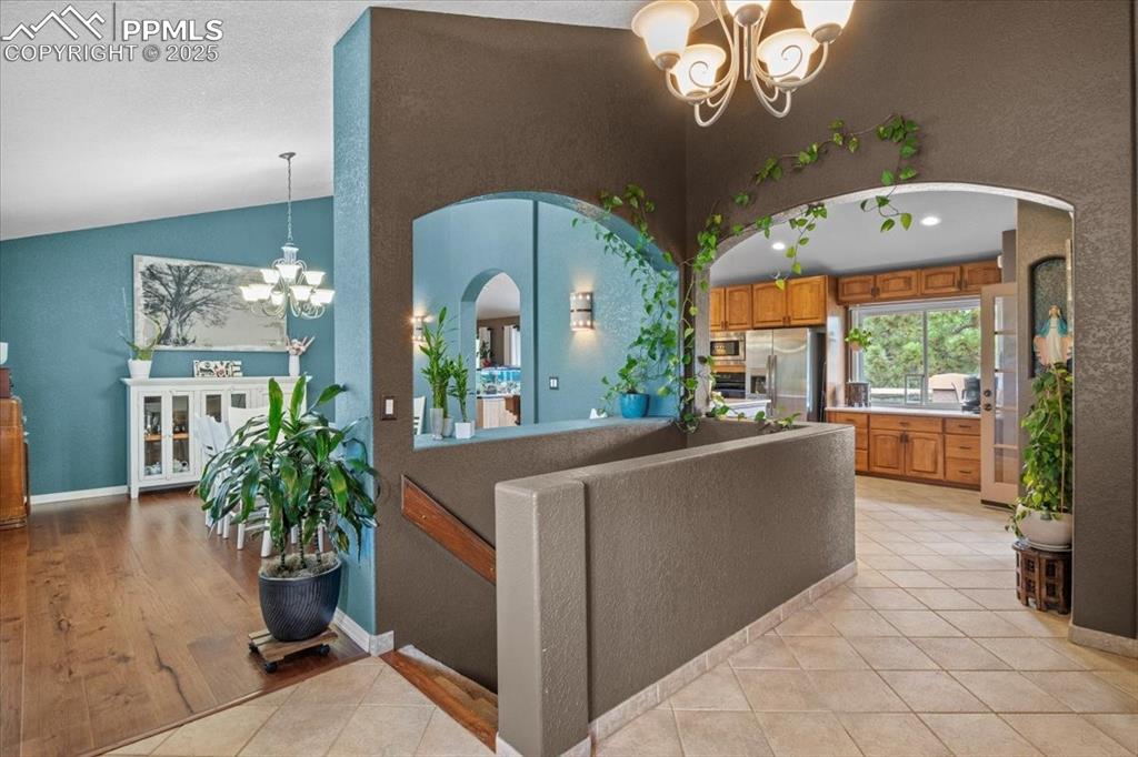 Image 6 of 49: Living area with a chandelier, arched walkways, light tile patterned floors
