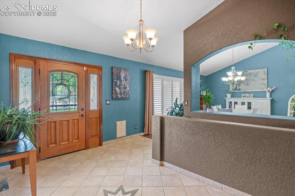 Image 7 of 49: Foyer entrance featuring a chandelier, light tile patterned flooring, vault