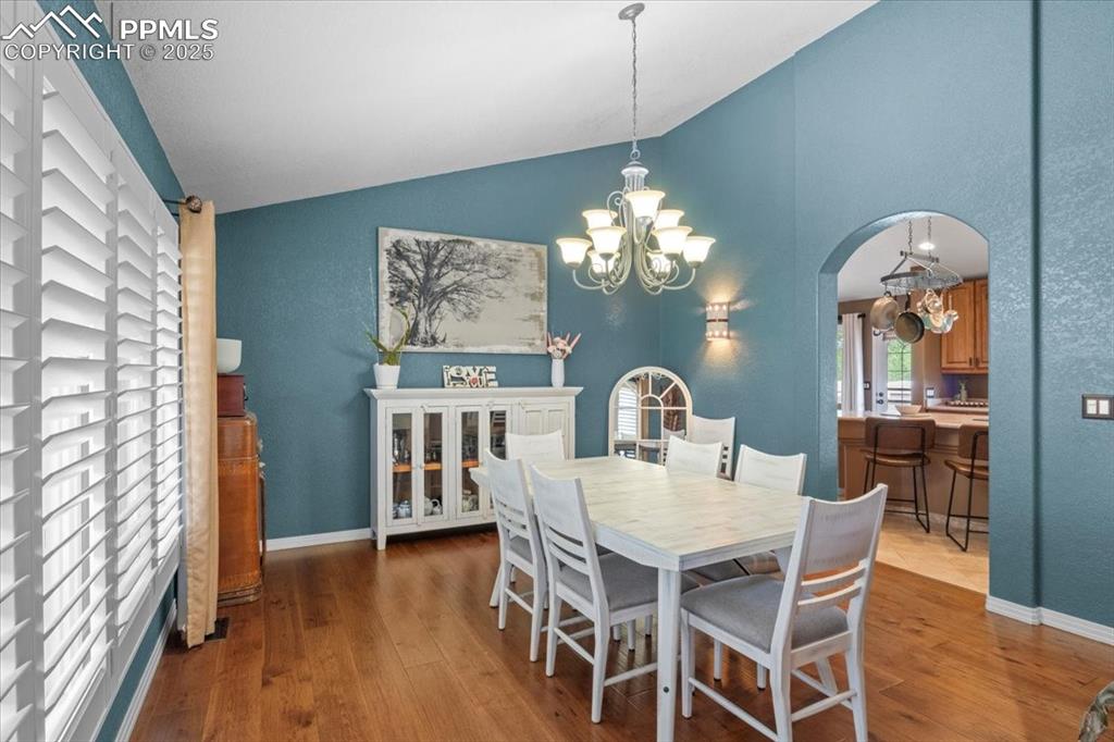 Image 9 of 49: Dining area featuring vaulted ceiling, a chandelier, arched walkways, and w