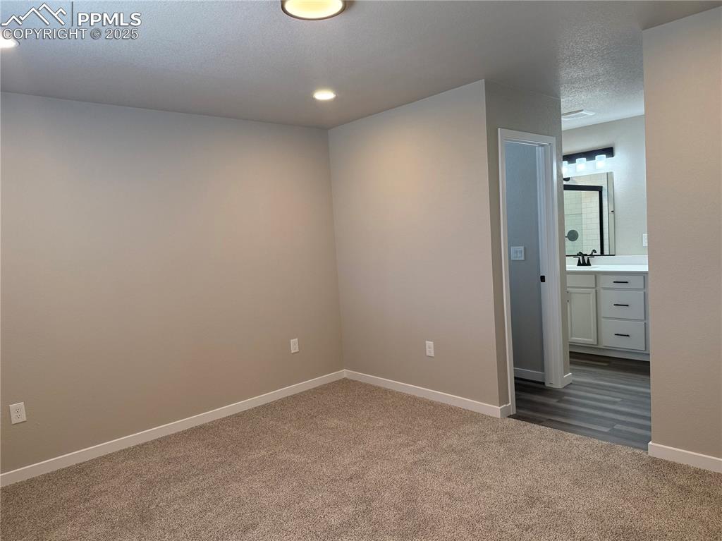 Image 5 of 8: Spare room with dark colored carpet, a textured ceiling, and recessed light