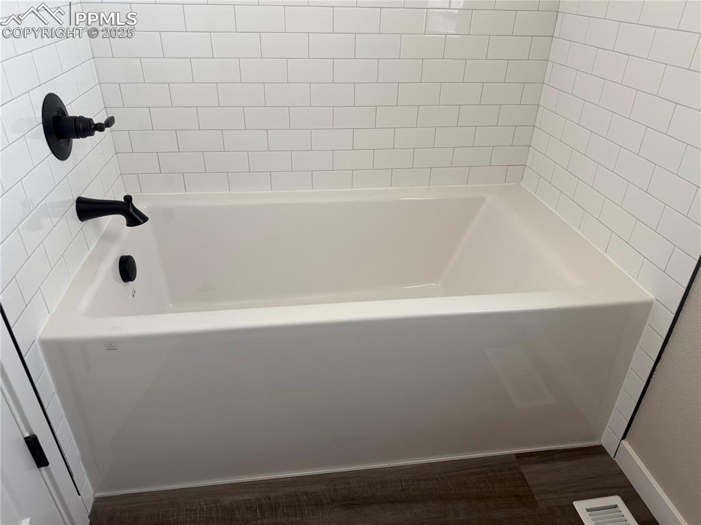 Image 7 of 8: Bathroom featuring a tub to relax in and wood finished floors
