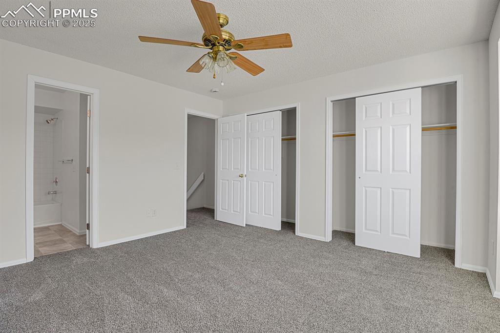Image 13 of 27: Unfurnished bedroom featuring multiple closets, a textured ceiling, light c