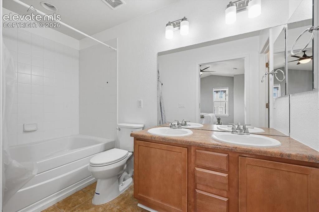 Image 19 of 34: Dual vanity with integrated sinks, wood-finish cabinetry, and a full-width