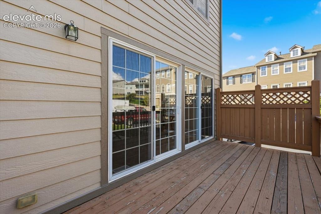 Image 30 of 34: Wood deck with privacy lattice fencing, tan siding, and sliding glass doors