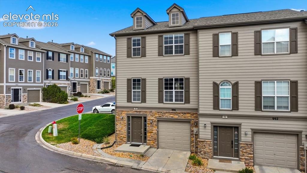 Image 7 of 34: Multi-story end unit townhome featuring stone and siding exterior, multiple