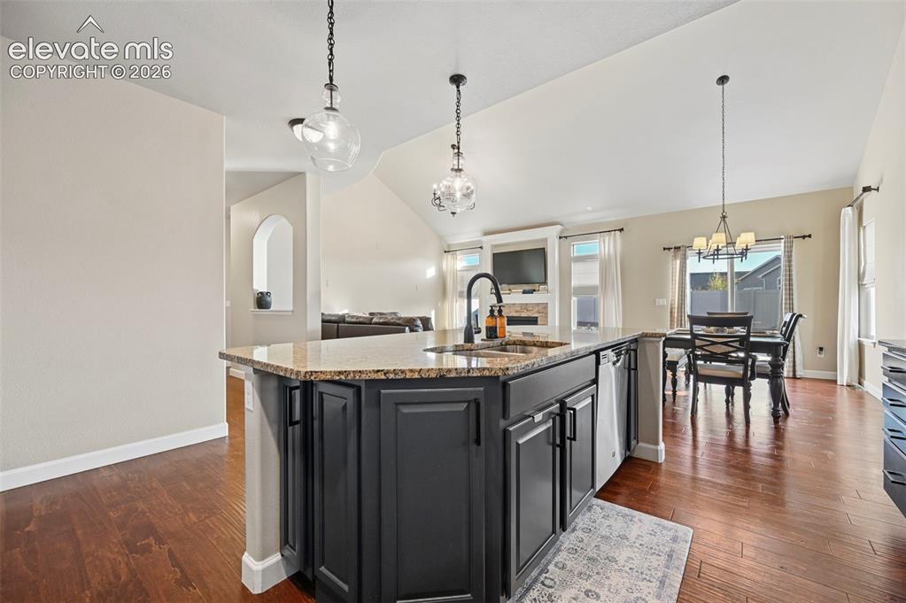 Image 10 of 47: Kitchen island featuring a sink with a matte black faucet, dark cabinetry, 